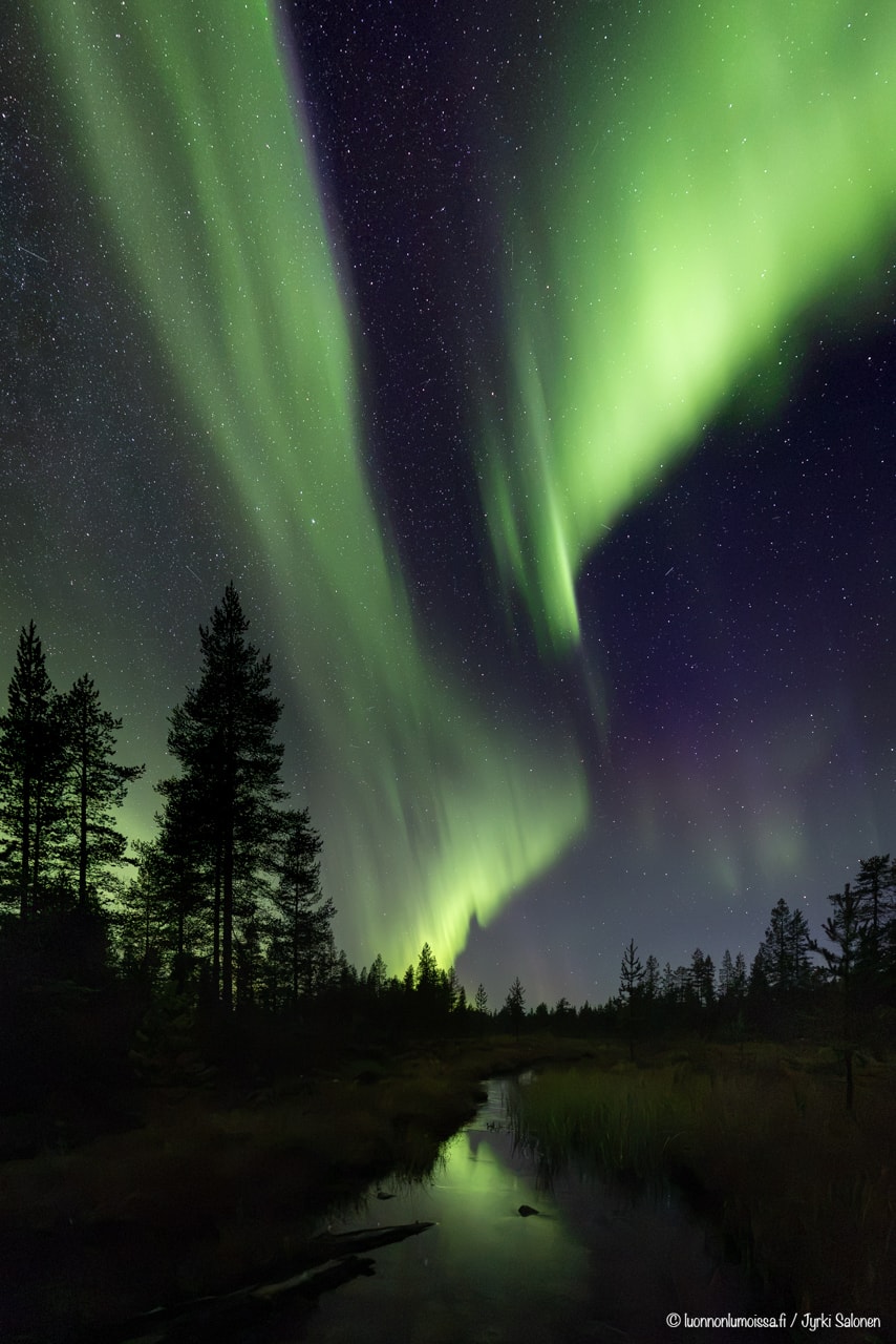 Revontulet leimuavat pienen joen yllä