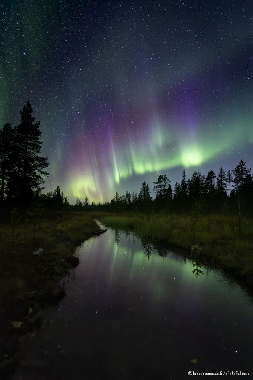 Revontulet leimuavat pienen joen yllä